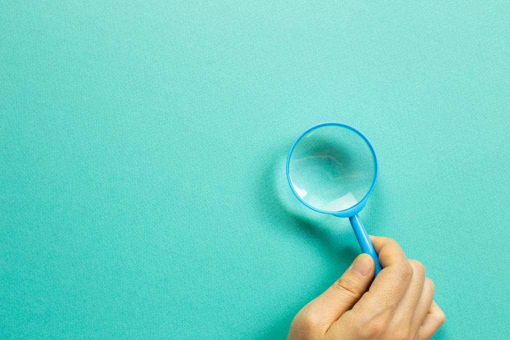 hand holding magnifying glass - aqua