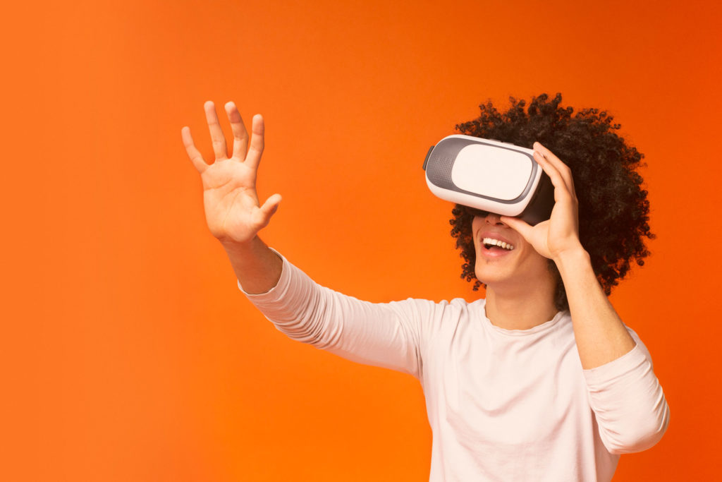 guy enjoying virtual reality glasses, pushing invisible button, orange panorama background
