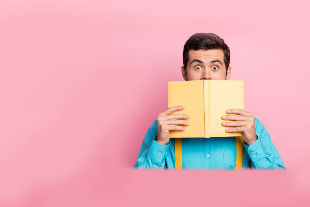Person holding an open book with an engaged expression, representing sales playbooks that are practical, engaging, and useful for sellers in their day-to-day work