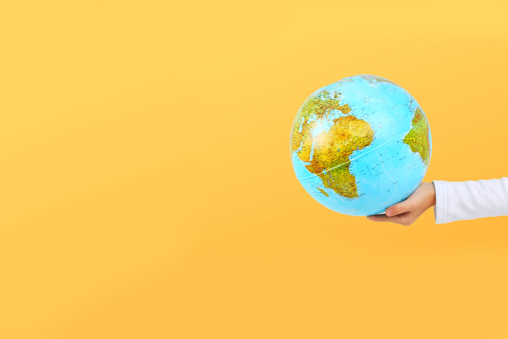 hand holding globe with bright yellow background
