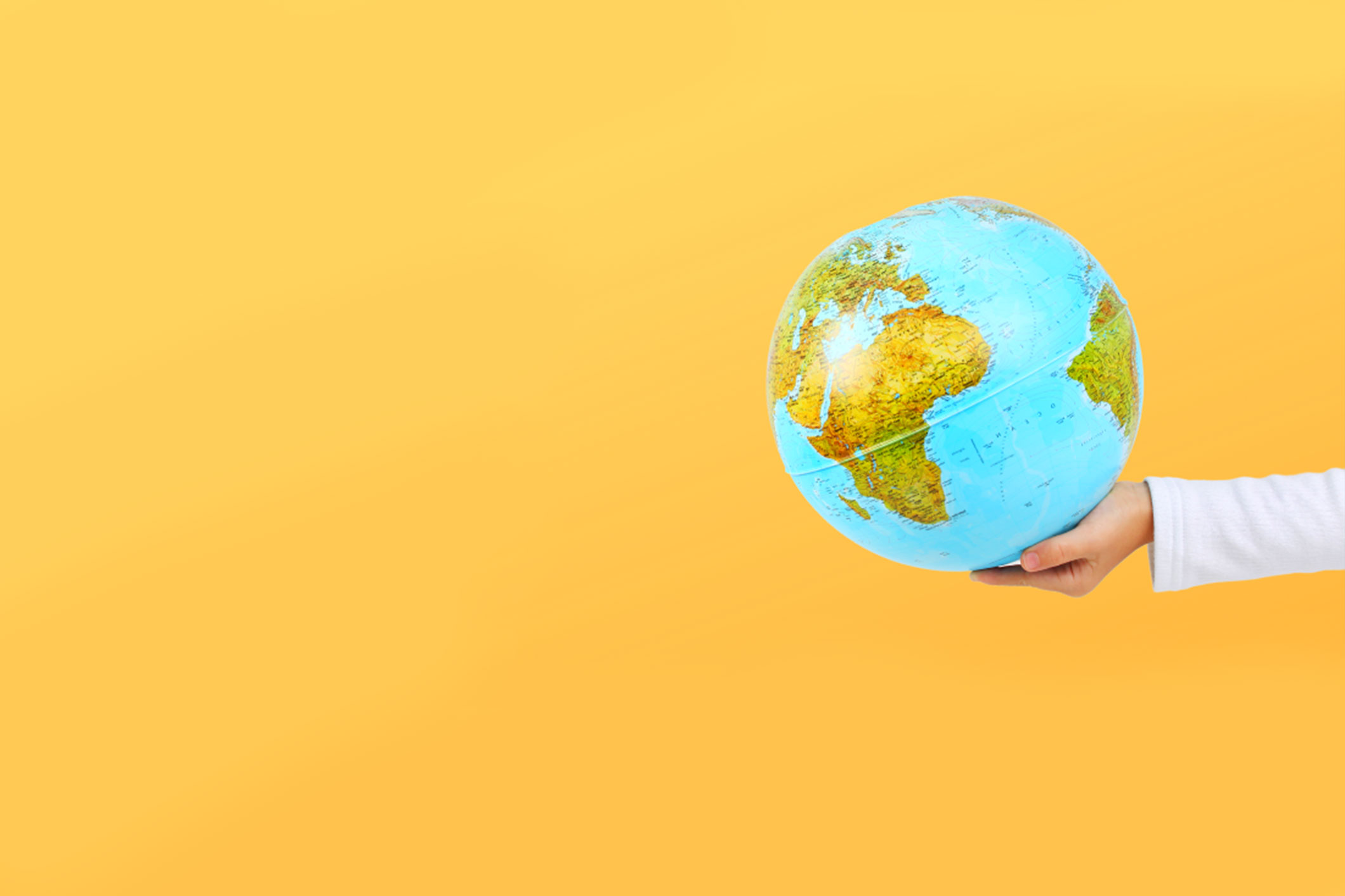 hand holding globe with bright yellow background