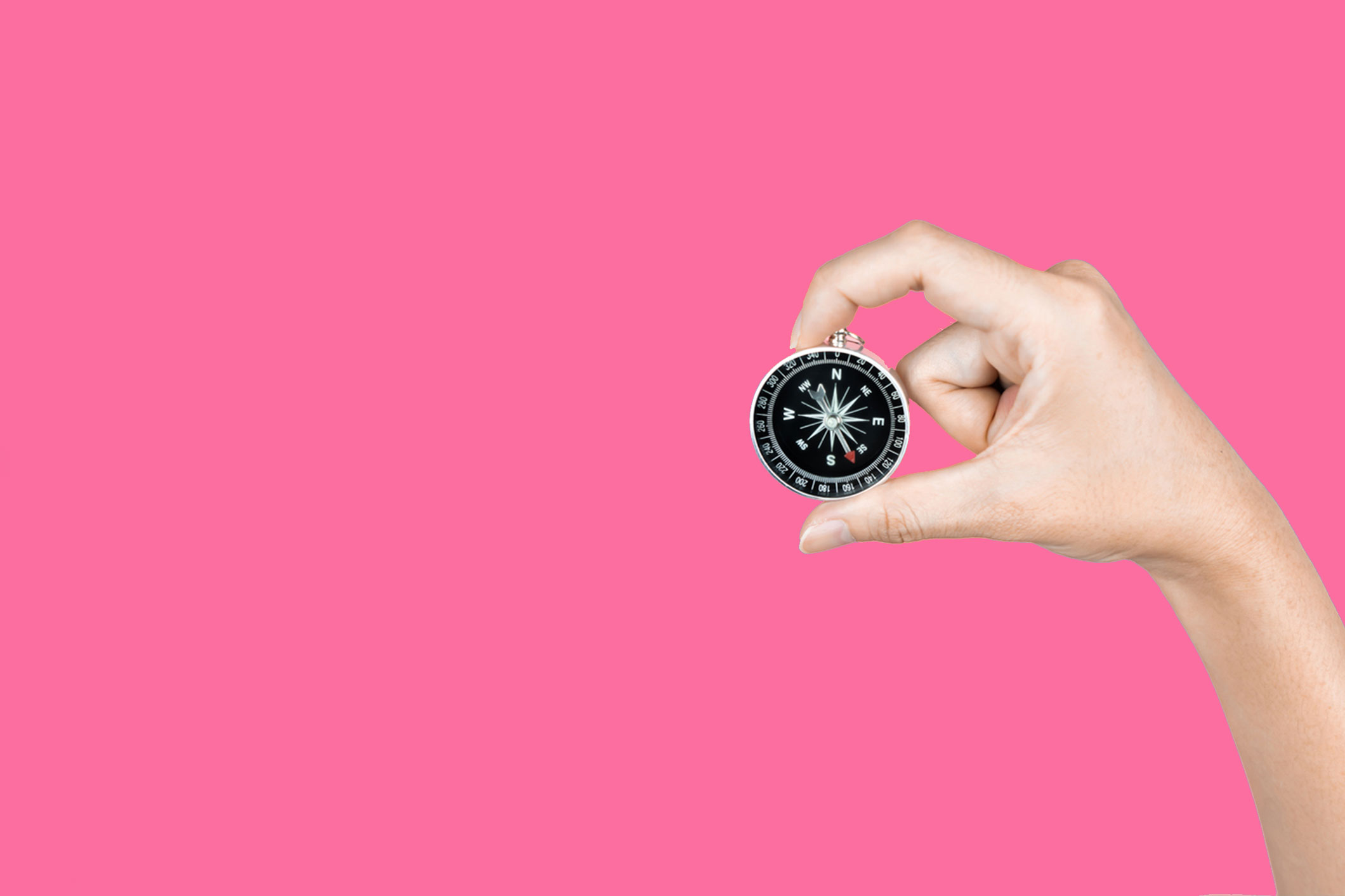 hand holding compass against bright pink background image for marketing blog