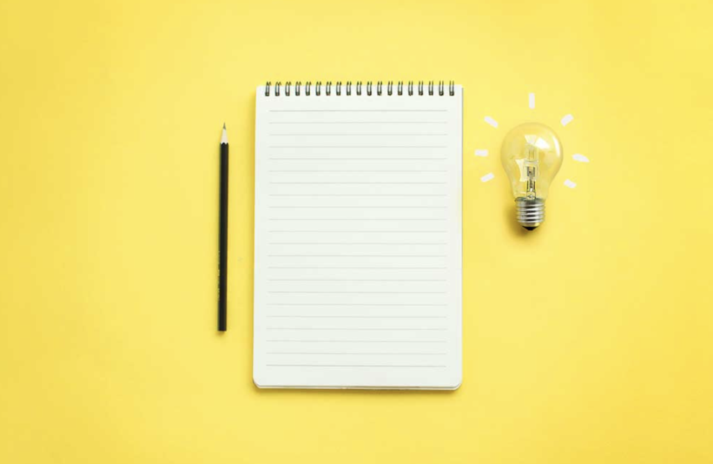 pencil notebook and lightbulb against bright yellow background