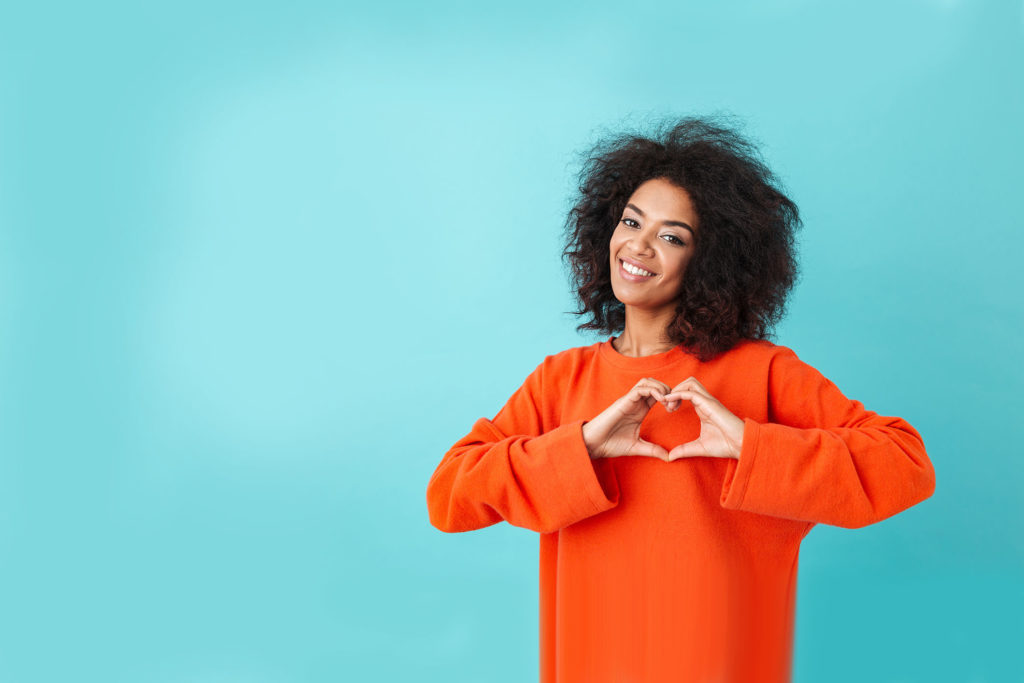 american woman in colorful shirt looking on camera and gesturing heart shape with hands, isolated over blue background for Product Marketing’s Shift to External Expertise