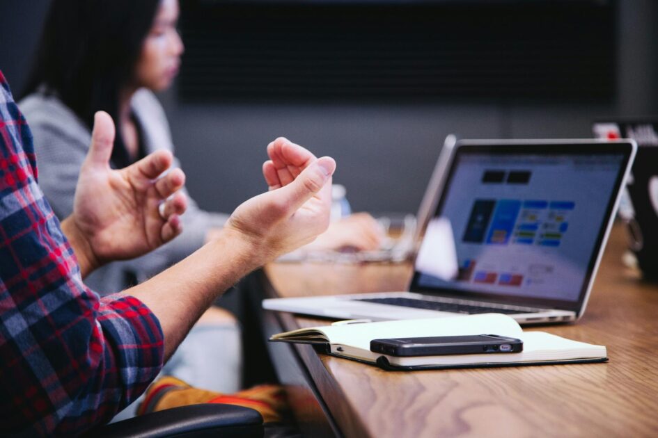 A sales professional sits in front of their laptop, explaining ideas to the product marketing and campaign management teams.
