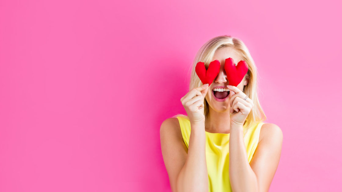 Happy woman holding heart in front of eyes for customer stories