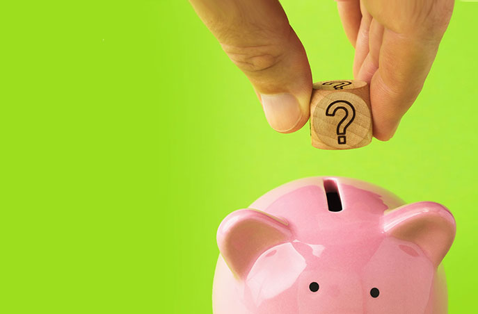 hand holding a wooden cube with a question mark near a piggy bank for budgetary guidance