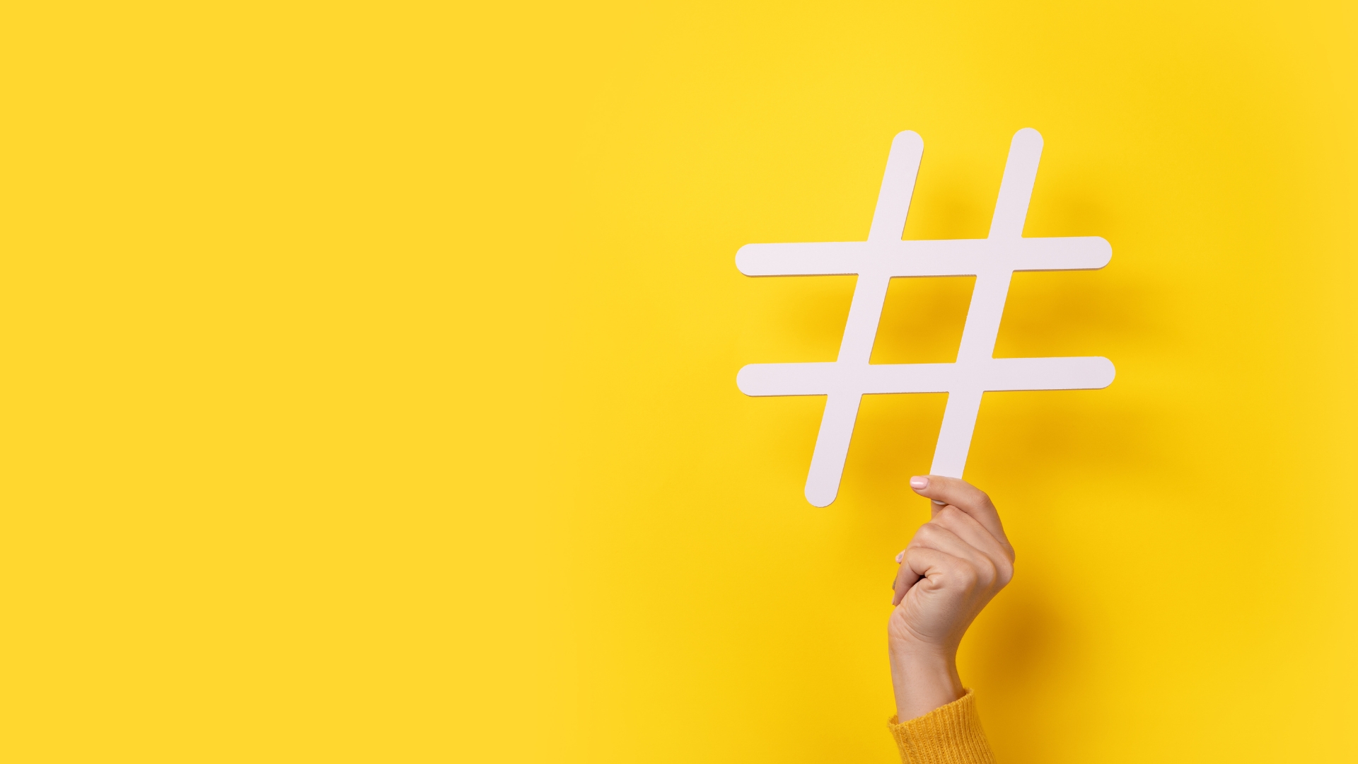 hand holding hashtag sign on yellow background for saas product marketing