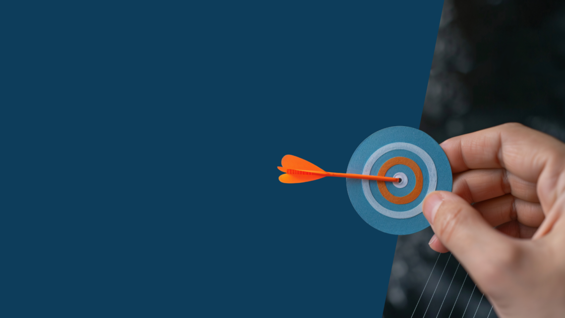 Hand placing a dart in the center of a target, symbolizing sales enablement strategies that help sellers move from pitch to paycheck with focused, practical tools.